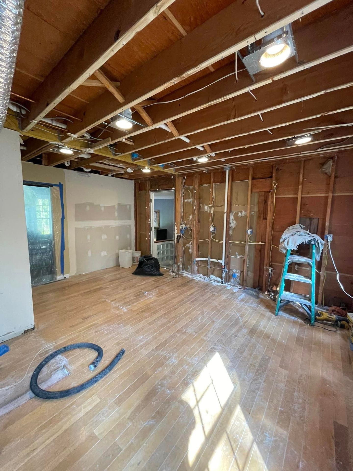 Interior of a room under renovation with exposed wooden beams, unfinished walls, and scattered construction tools.